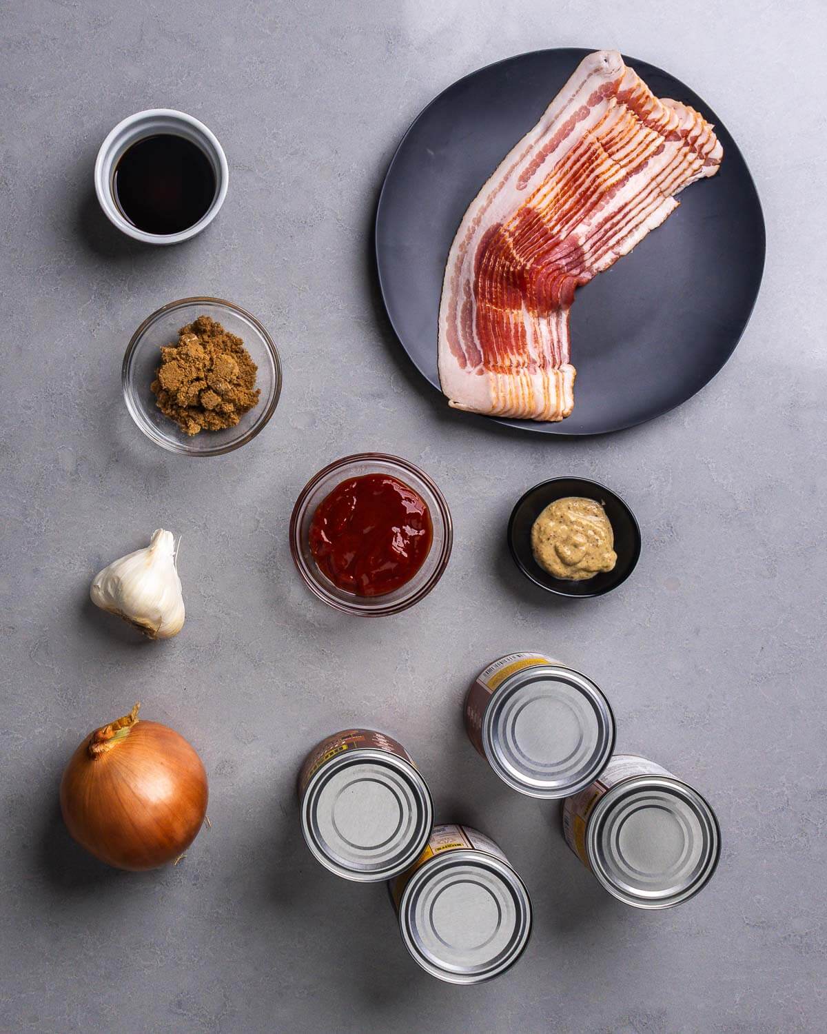 Ingredients shown: worcestershire sauce, brown sugar, bacon, ketchup, brown mustard, garlic, onion, and 4 cans of baked beans.