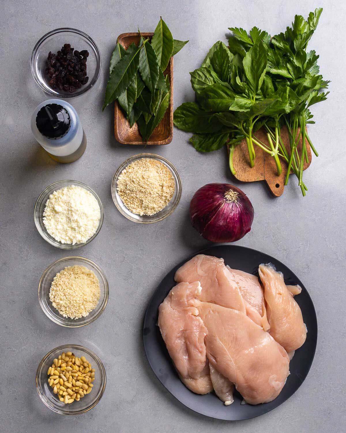 Ingredients shown: raisins, olive oil, bay leaves, basil, parsley, pecorino, panko breadcrumbs, onion, pine nuts, and chicken cutlets.