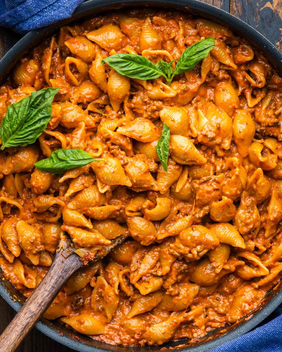 Creamy beef and shells pasta in large black pan.