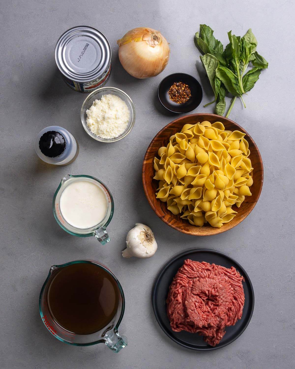 Ingredients shown: canned plum tomatoes, onion, hot red pepper flakes, basil, pecorino, olive oil. cream, garlic, shell pasta, beef stock, and ground chuck beef.