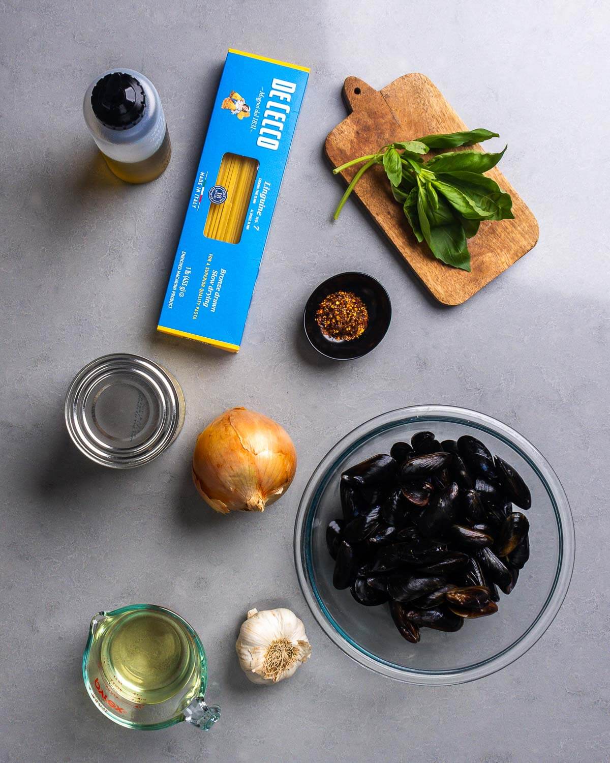 Ingredients shown: olive oil, linguine, basil, hot red pepper flakes, tomatoes, onion, mussels, garlic, and white wine.