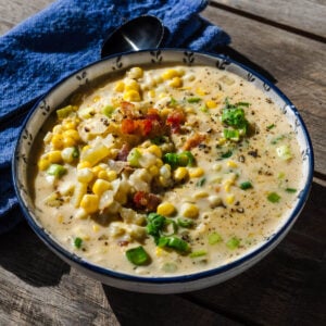 Corn chowder in bowl on table outside.