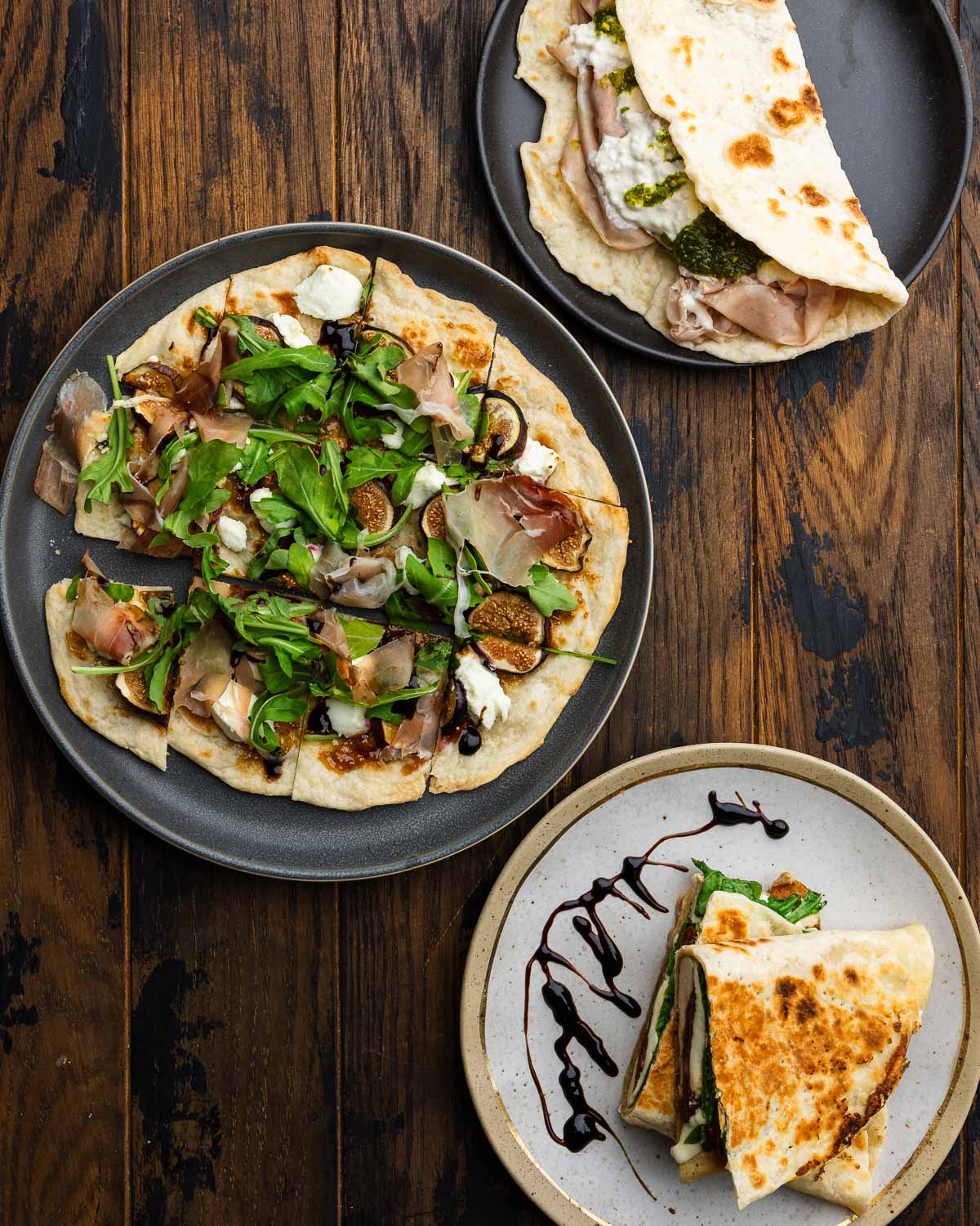 Three flatbreads made into a mortadella sandwich, fig and goat cheese pizza-style flatbread, and grilled chicken panini style.