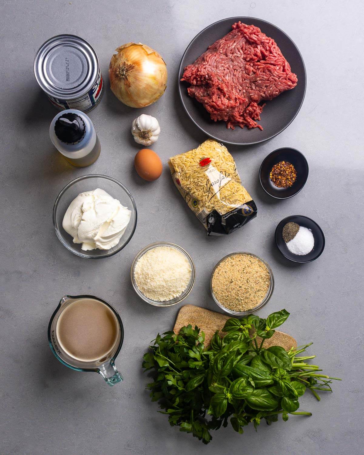 Ingredients shown: tomatoes, olive oil, onion, garlic, eggs, ground beef, ricotta, orzo, hot red pepper flakes, salt, pepper, grated parmesan, breadcrumbs, beef stock, parsley, and basil.