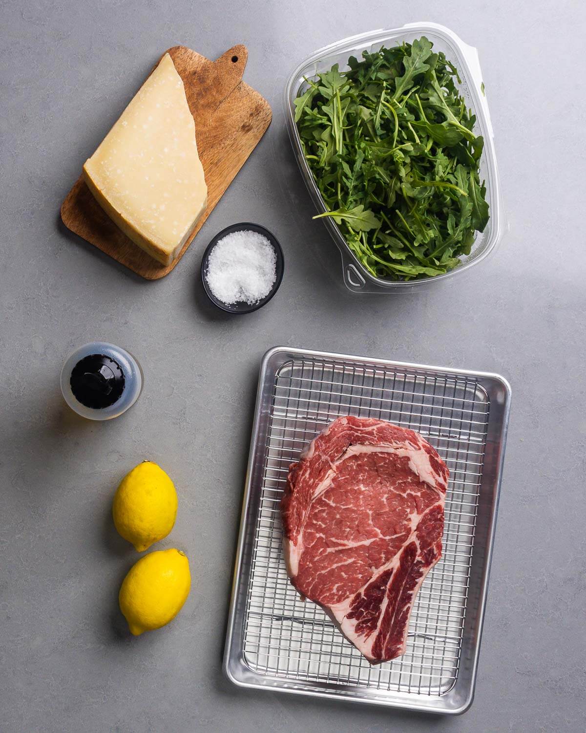 Ingredients shown: Parmigiano Reggiano, salt, arugula, olive oil, lemons, and ribeye steak.