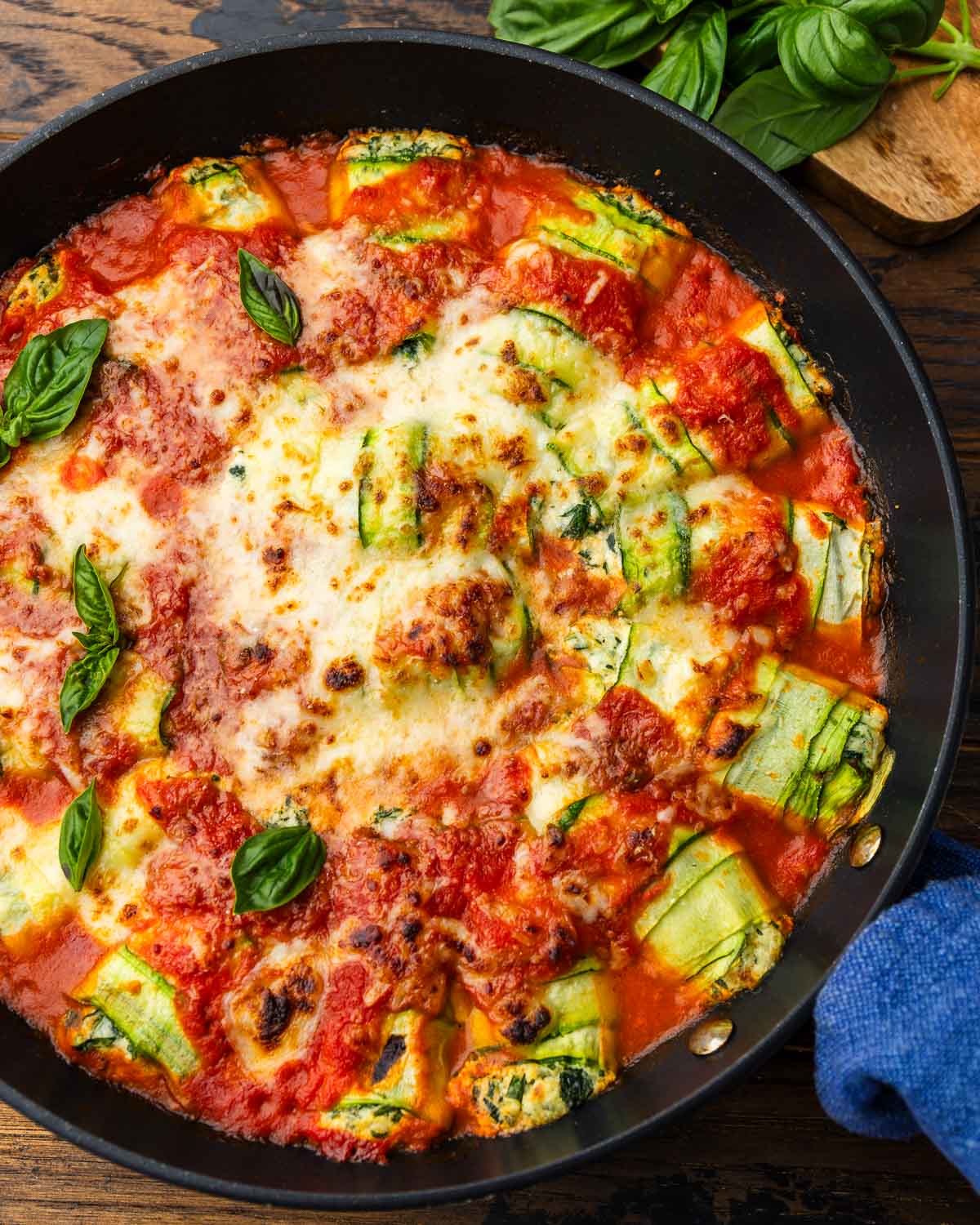 Zucchini rollatini in large black pan with basil on the side.