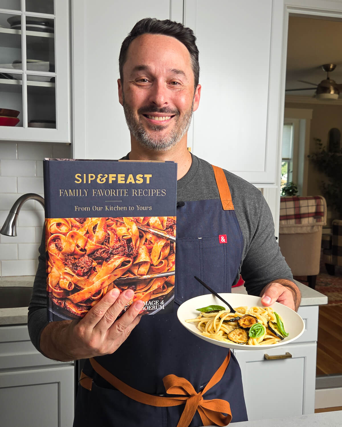 Jim holding a copy of his cookbook and a plate of spaghetti alla Nerano.