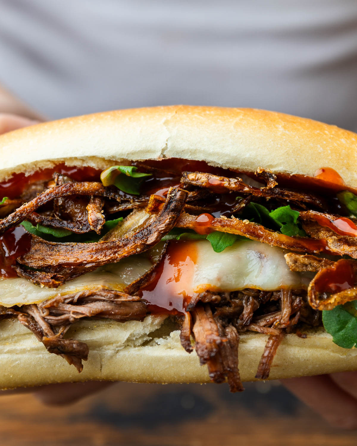 Closeup shot of chuck roast sandwich with melted cheese and crispy onions.