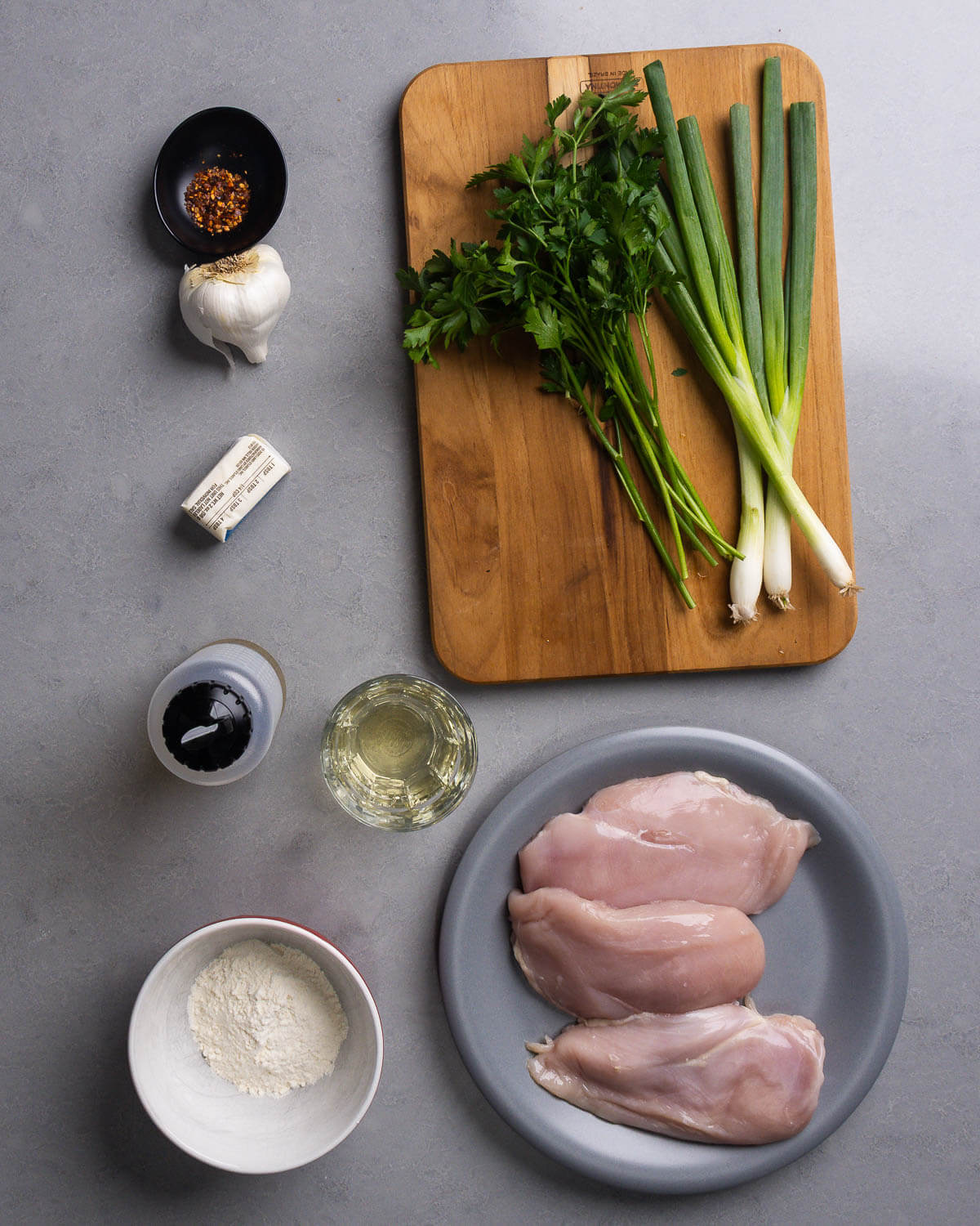 Ingredients shown: hot red pepper flakes, garlic, parsley, green onions, butter, olive oil, wine, flour, and chicken breasts.