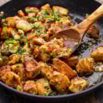 Garlic butter chicken bites scooped with wooden spoon.