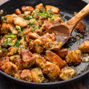 Garlic butter chicken bites scooped with wooden spoon.