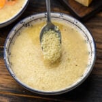 Spoonful of pastina held over bowl of pastina in brodo.