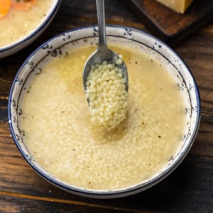 Spoonful of pastina held over bowl of pastina in brodo.