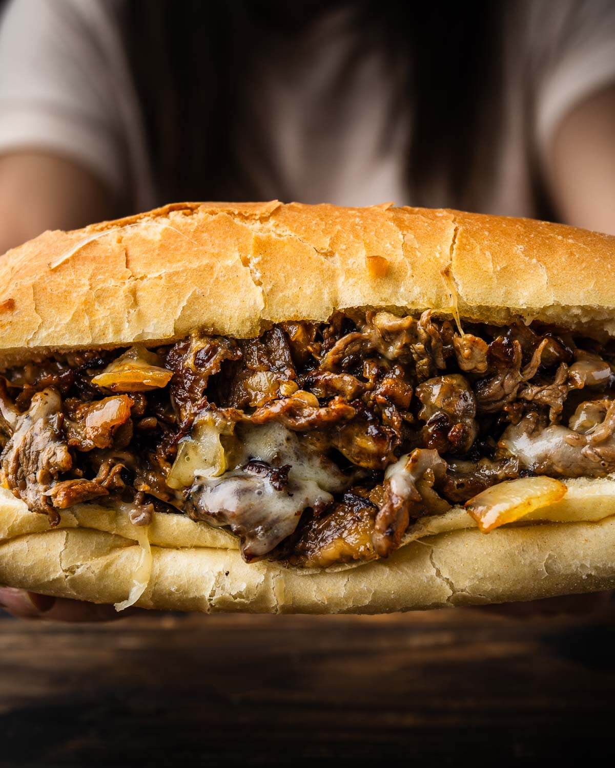 Hands holding Philly cheesesteak.