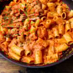 Large pan with spicy vodka rigatoni with sliced chicken cutlets.