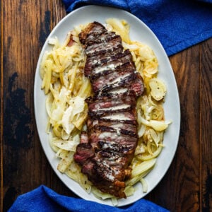 Strip steak with gorgonzola sauce on white platter.
