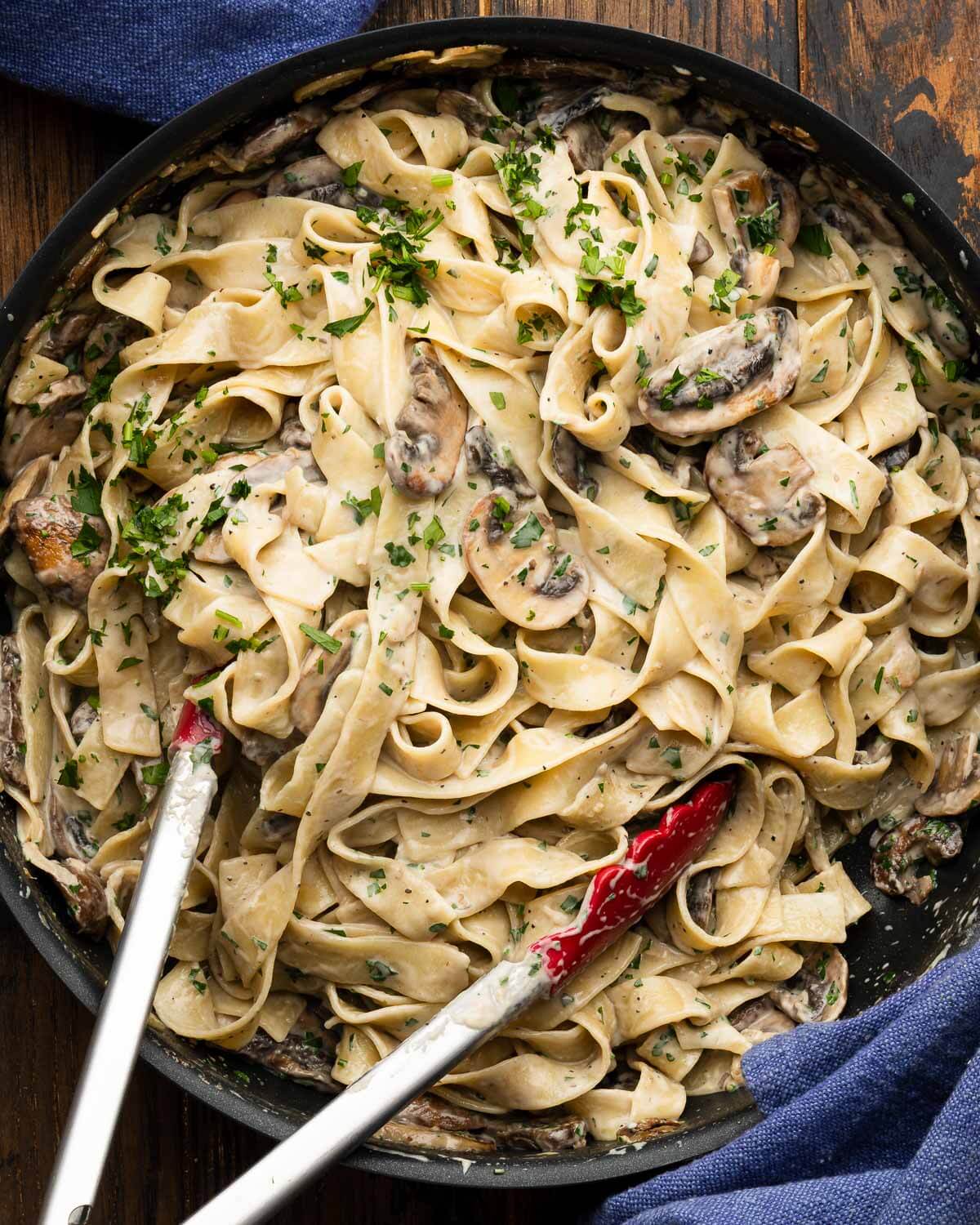 Creamy garlic mushroom pasta in black pan.