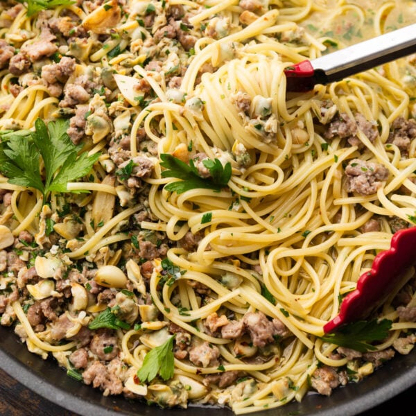 Linguine with sausage and clams in black pan.