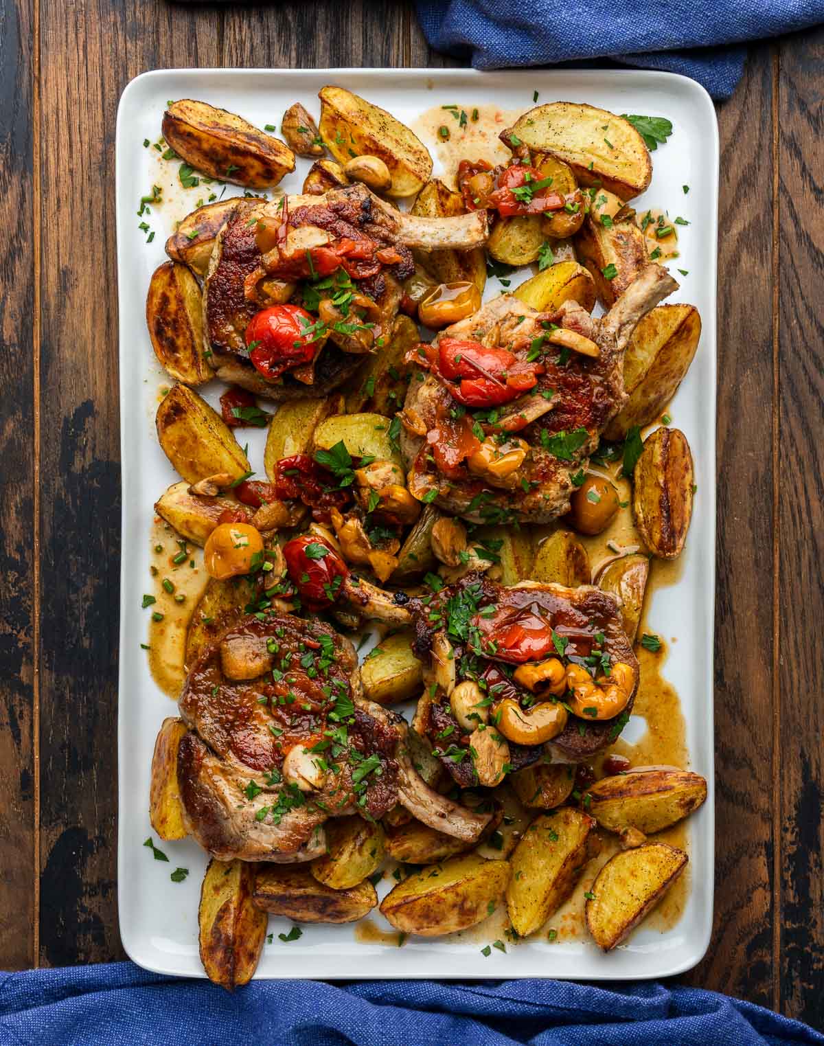 Large platter with pork chops, roasted potatoes, and peppadew peppers.