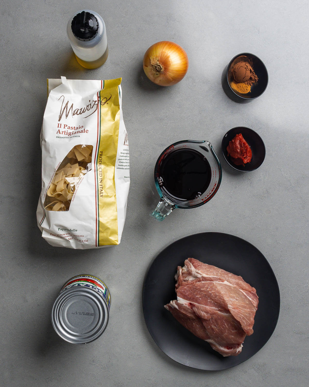 Ingredients shown: olive oil, onion, cocoa powder, cinnamon, red wine, tomato paste, canned tomatoes, and pork shoulder.