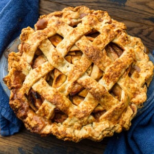 Baked apple pie on wood table with blue napkins.