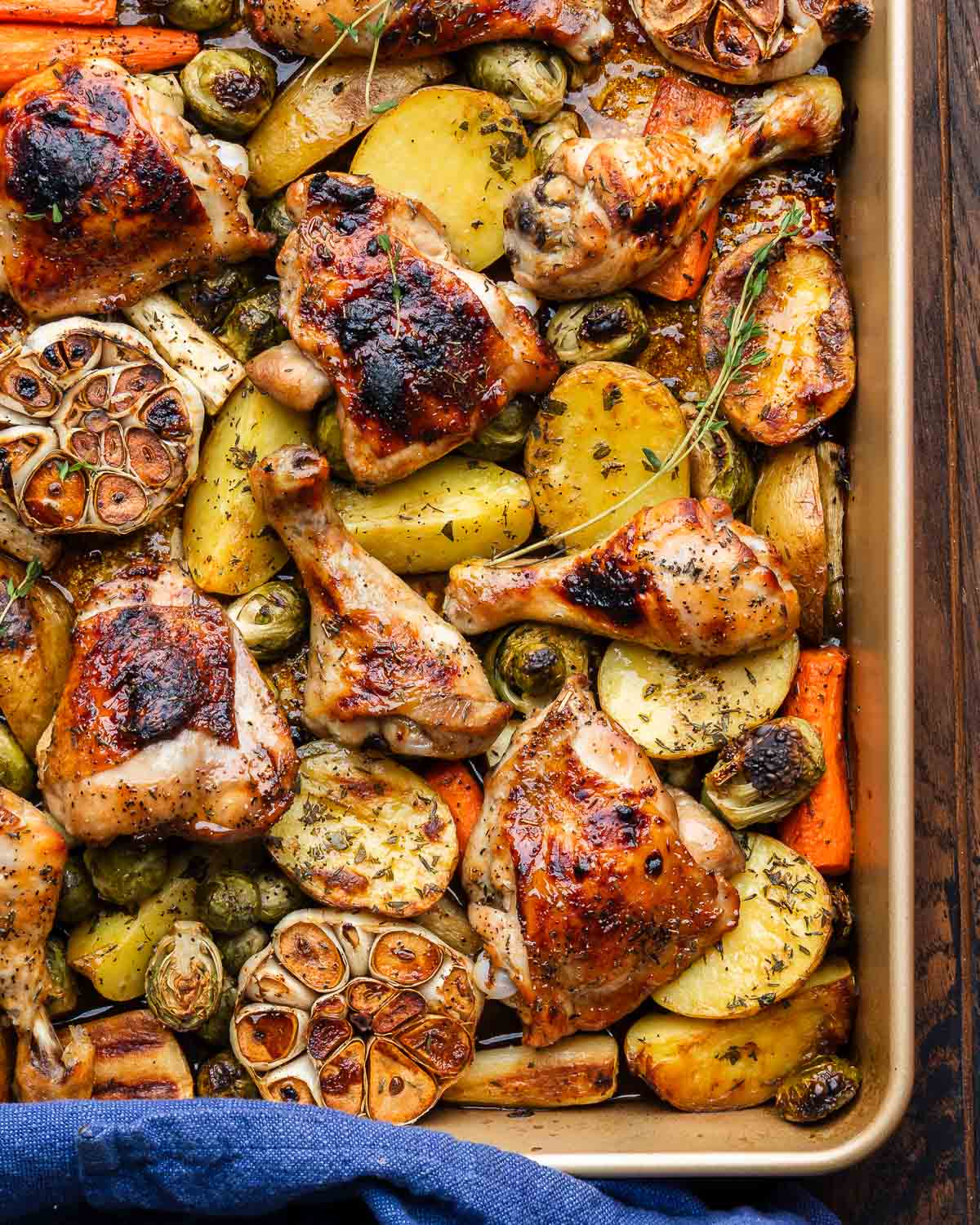 Large baking dish with maple roasted chicken, roasted garlic, and fall vegetables.