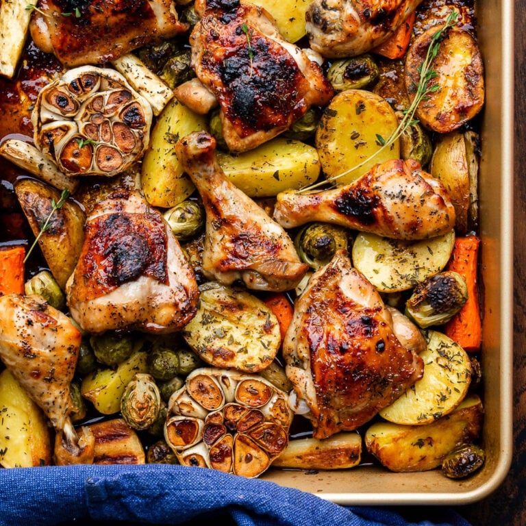 Large baking dish with maple roasted chicken, roasted garlic, and fall vegetables.