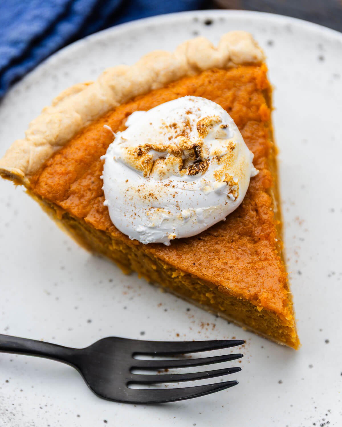 Slice of sweet potato pie and fork on white plate.
