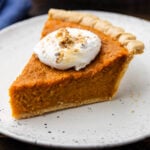 Slice of sweet potato pie with marshmallow topping on white plate.
