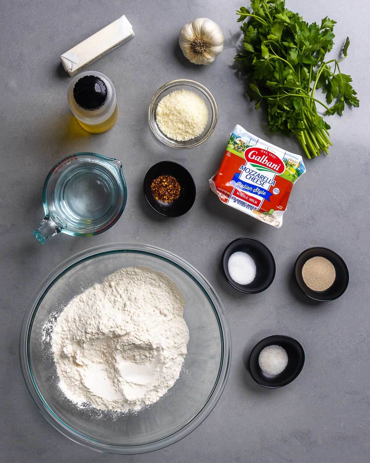 Ingredients shown: butter, garlic parsley, olive oil, pecorino romano, mozzarella, water, hot red pepper flakes, flour, salt, yeast, and sugar.