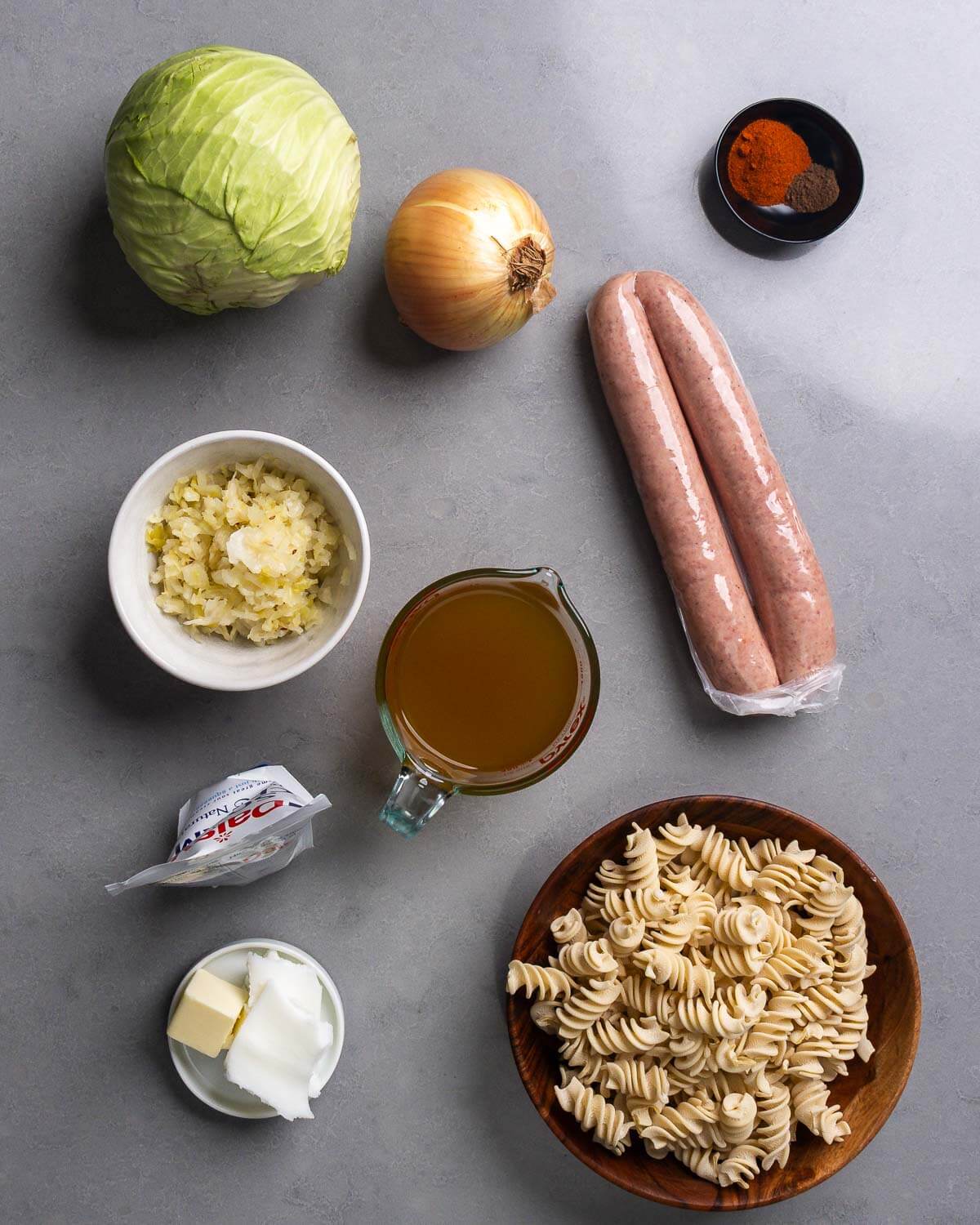 Ingredients shown: cabbage, onion, paprika, allspice, sauerkraut, chicken stock, sour cream, kielbasa, butter, lard, and pasta.