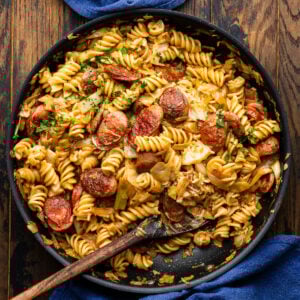 Kielbasa cabbage and sauerkraut pasta in large black pan.