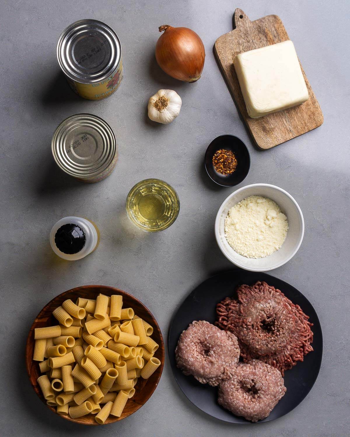 Ingredients shown: canned tomatoes, onion, garlic, mozzarella, wine, hot red pepper flakes, pecorino, olive oil, rigatoni, ground beef, and ground pork.
