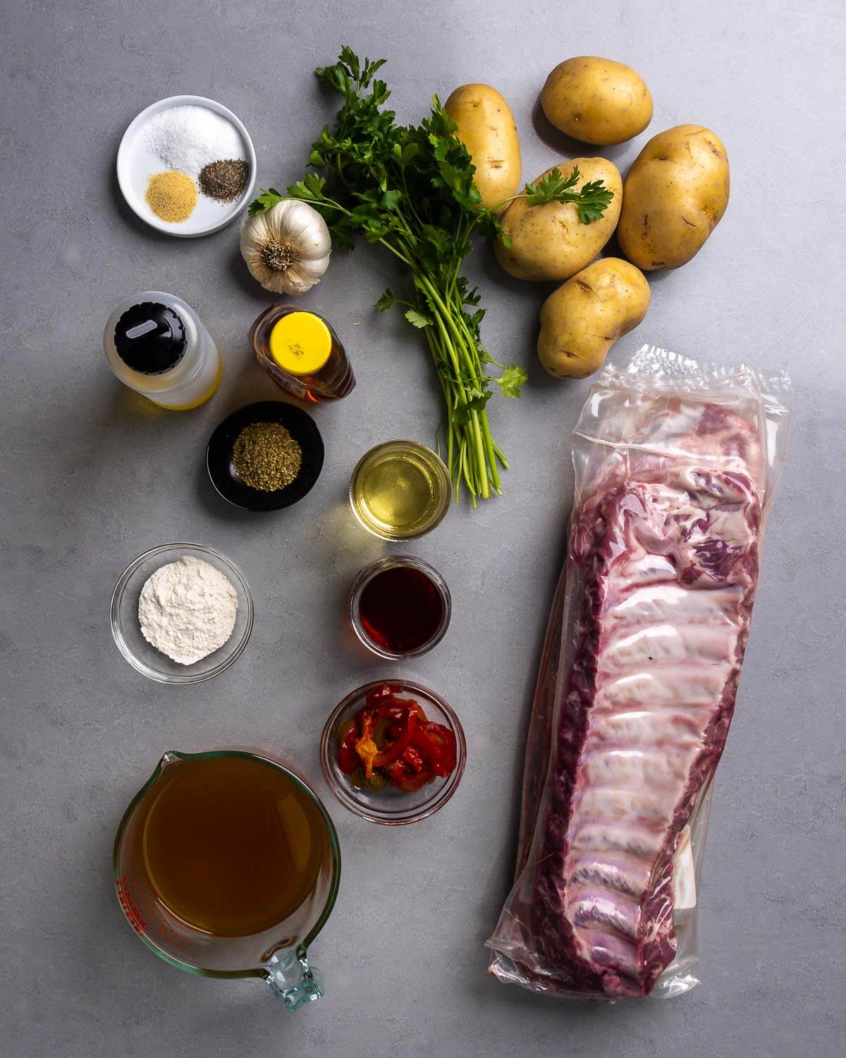 Ingredients shown: salt, pepper, granulated garlic, garlic, olive oil, honey, oregano, parsley, potatoes, white wine, red wine vinegar, flour, cherry peppers, baby back ribs, and chicken stock.