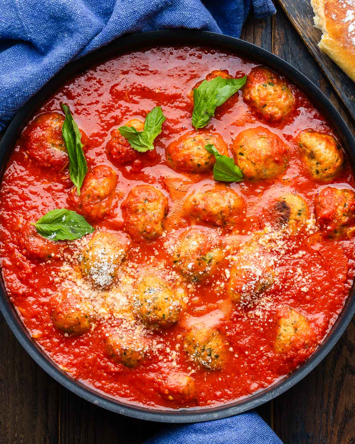 Large black pan with chicken meatballs in marinara sauce.