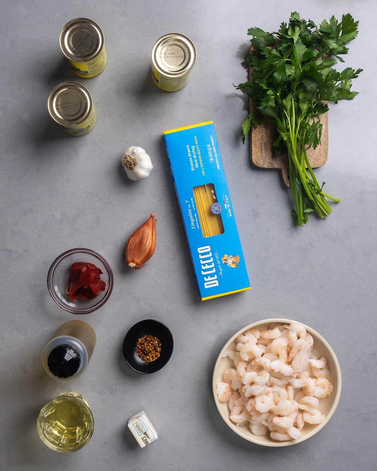 Ingredients shown: canned clams, parsley, garlic, shallot, pasta, tomato paste, olive oil, hot red pepper flakes, shrimp, white wine, and butter.