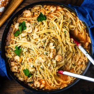 Clam and baby shrimp pasta in large black pan.