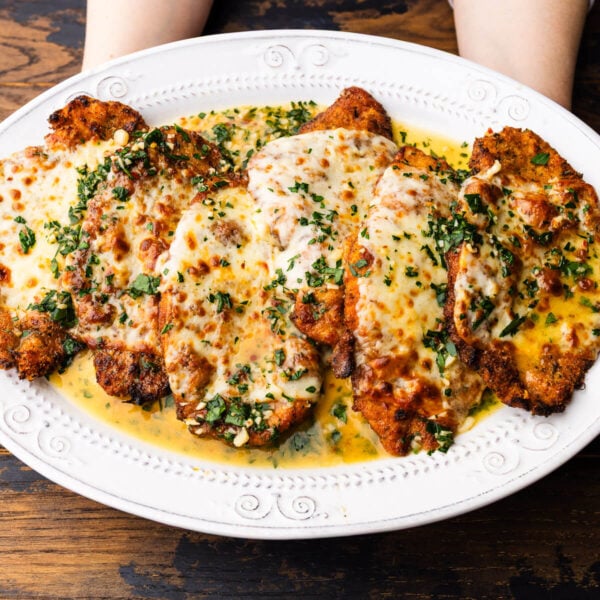 Hands holding platter of chicken scampi.