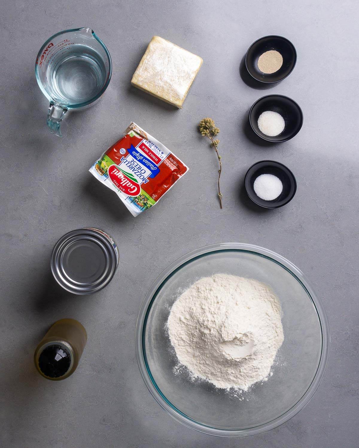 Ingredients shown: water, cheddar cheese, mozzarella, Sicilian oregano, yeast, sugar, salt, canned tomatoes, olive oil, and bread flour.