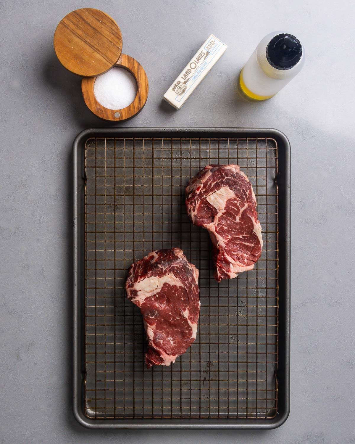 Ingredients shown: salt, butter, neutral oil, and ribeye steaks.