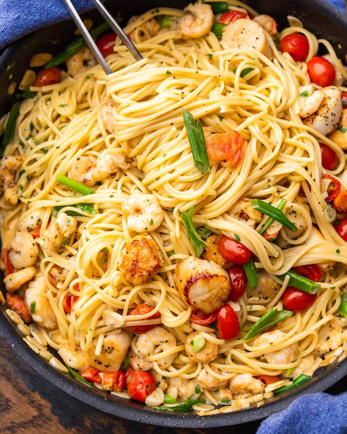 Creamy seafood pasta in black pan.