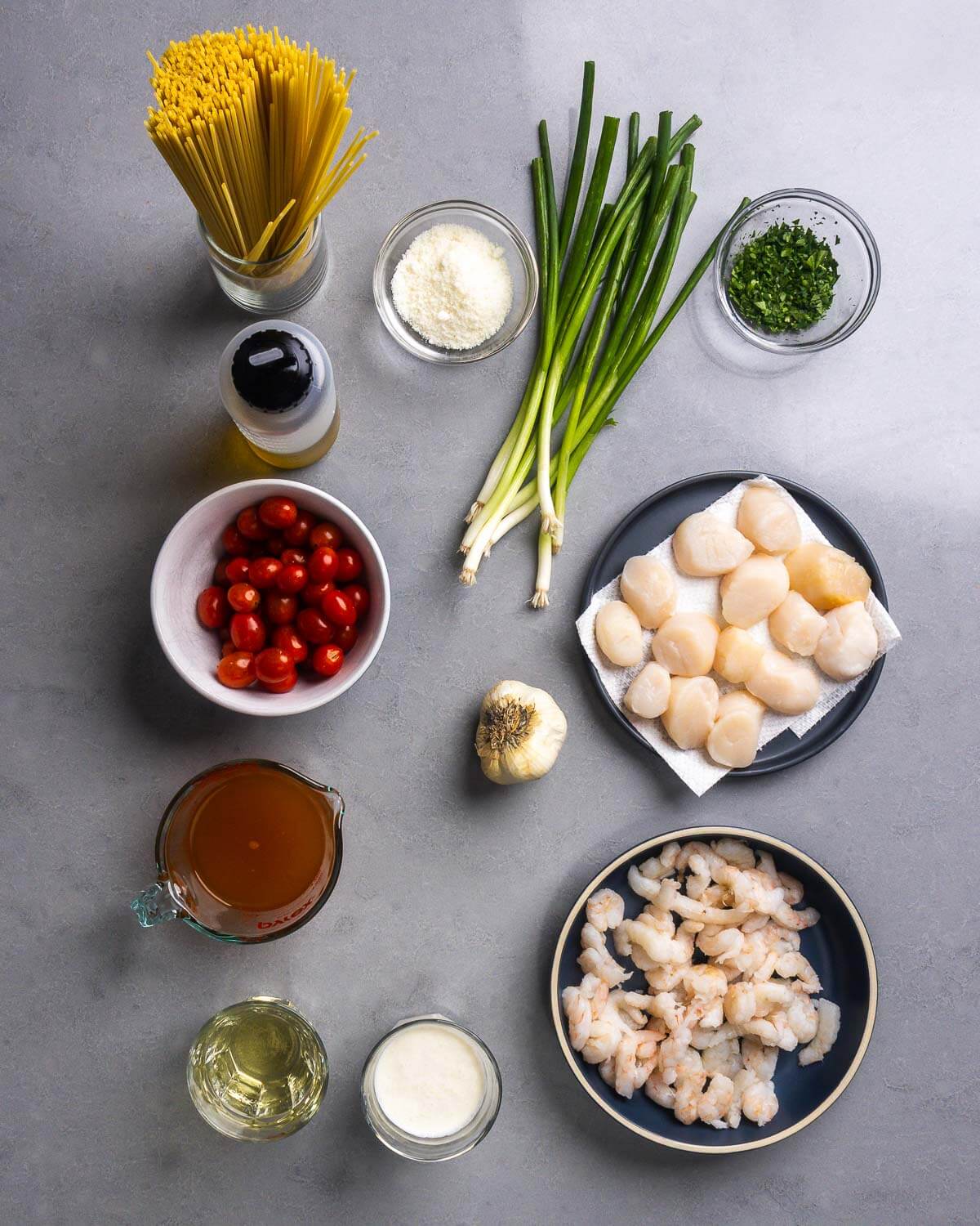 Ingredients shown: fine linguine, parmesan cheese, green onions, parsley, olive oil, cherry tomatoes, garlic, scallops, lobster stock, wine, heavy cream, and shrimp.