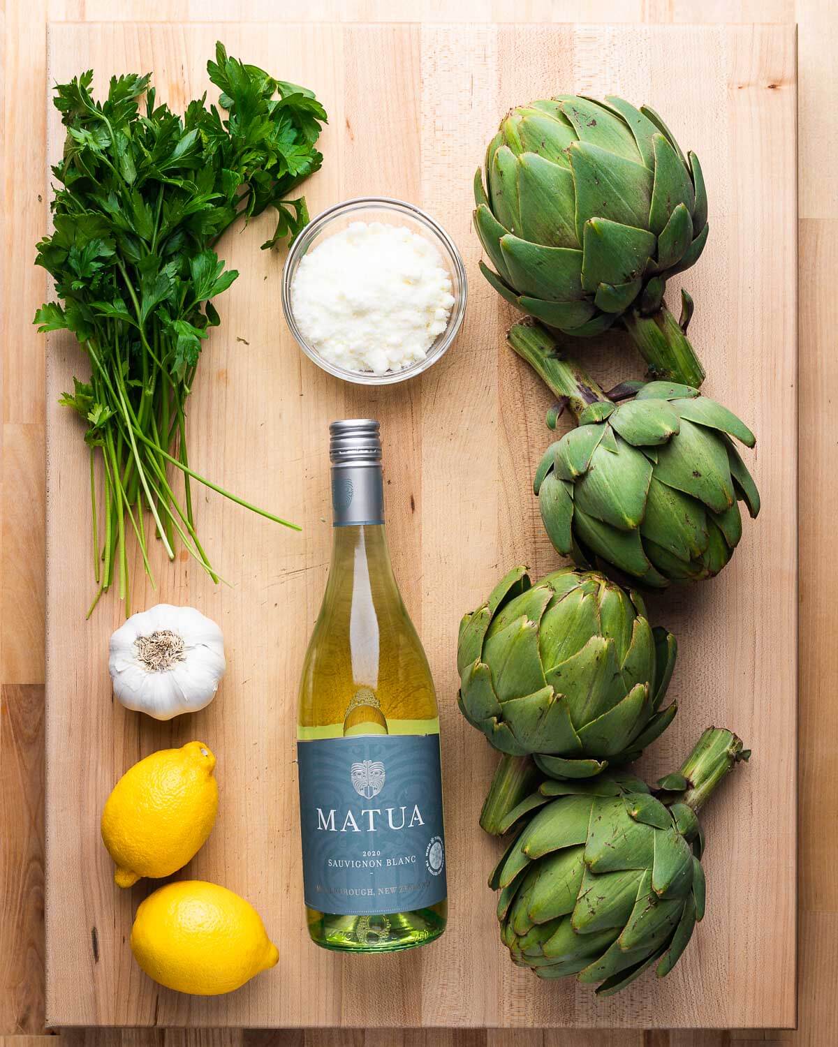 Ingredients shown: Italian flat-leaf parsley, grated romano cheese, artichokes, garlic, lemons, and white wine.