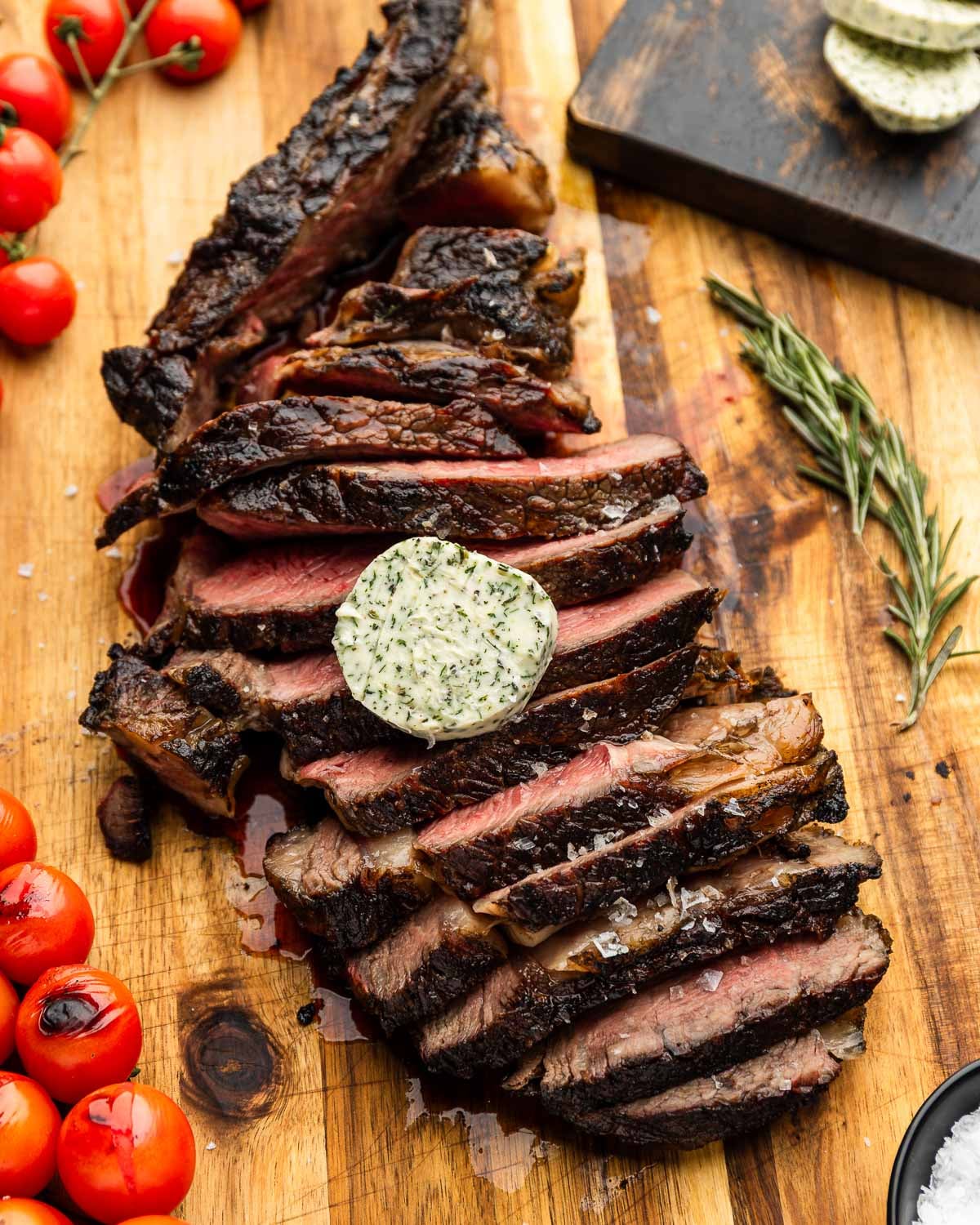 Sliced grilled tomahawk steak topped with compound butter and flaky sea salt.