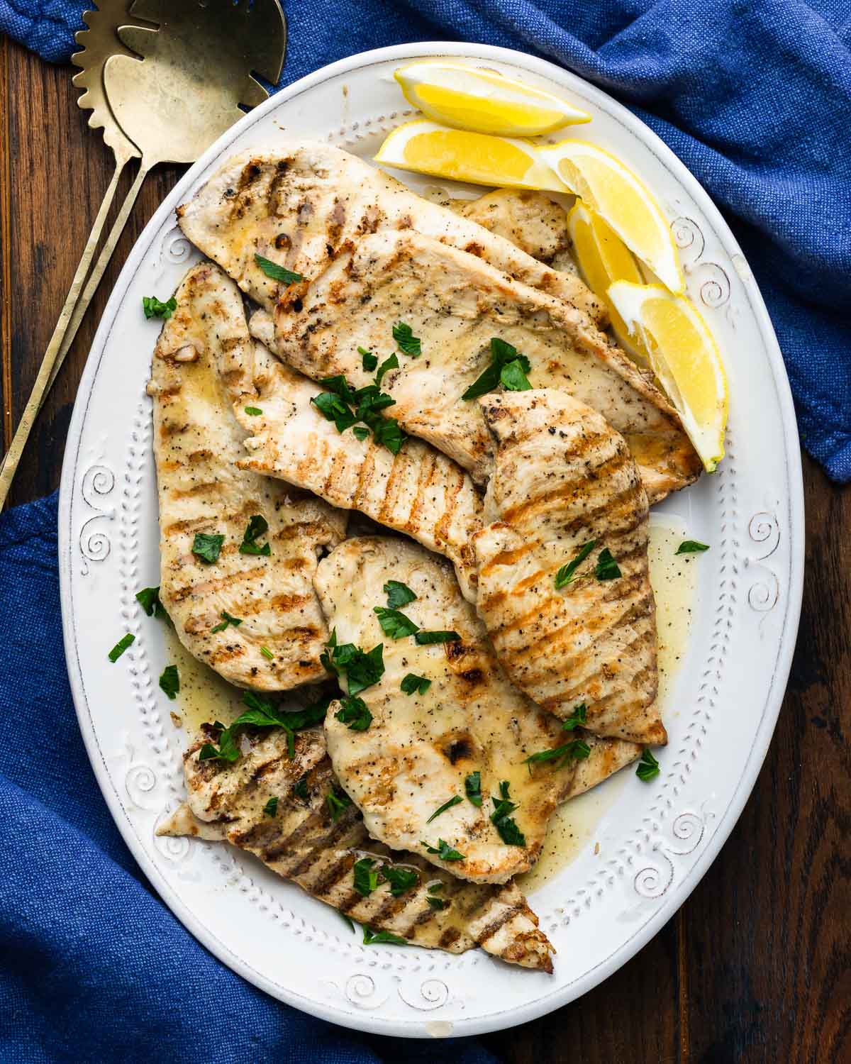 Platter of marinated grilled chicken with lemon wedges.