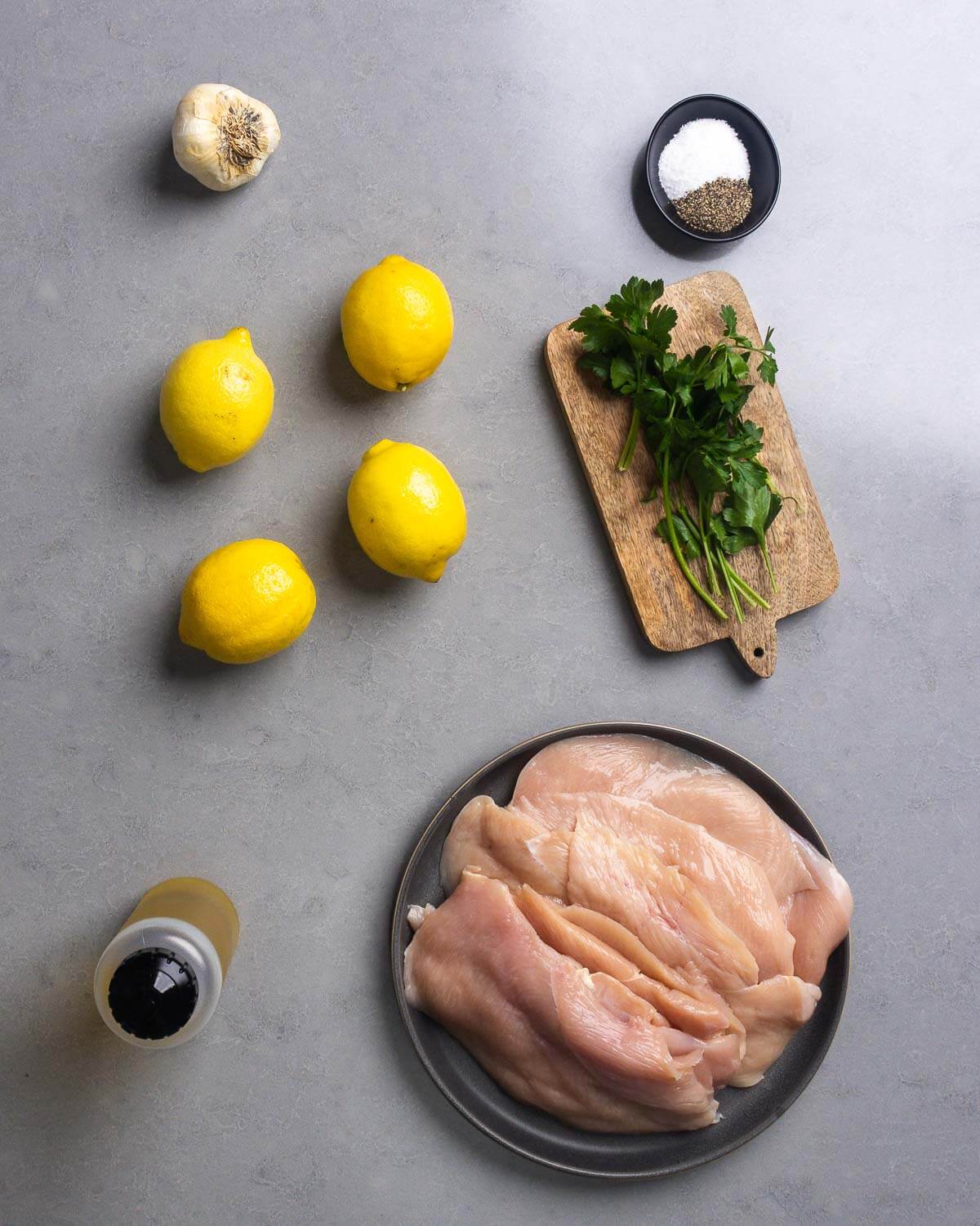 Ingredients shown: garlic, salt, pepper, lemons, parsley, olive oil, and chicken cutlets.