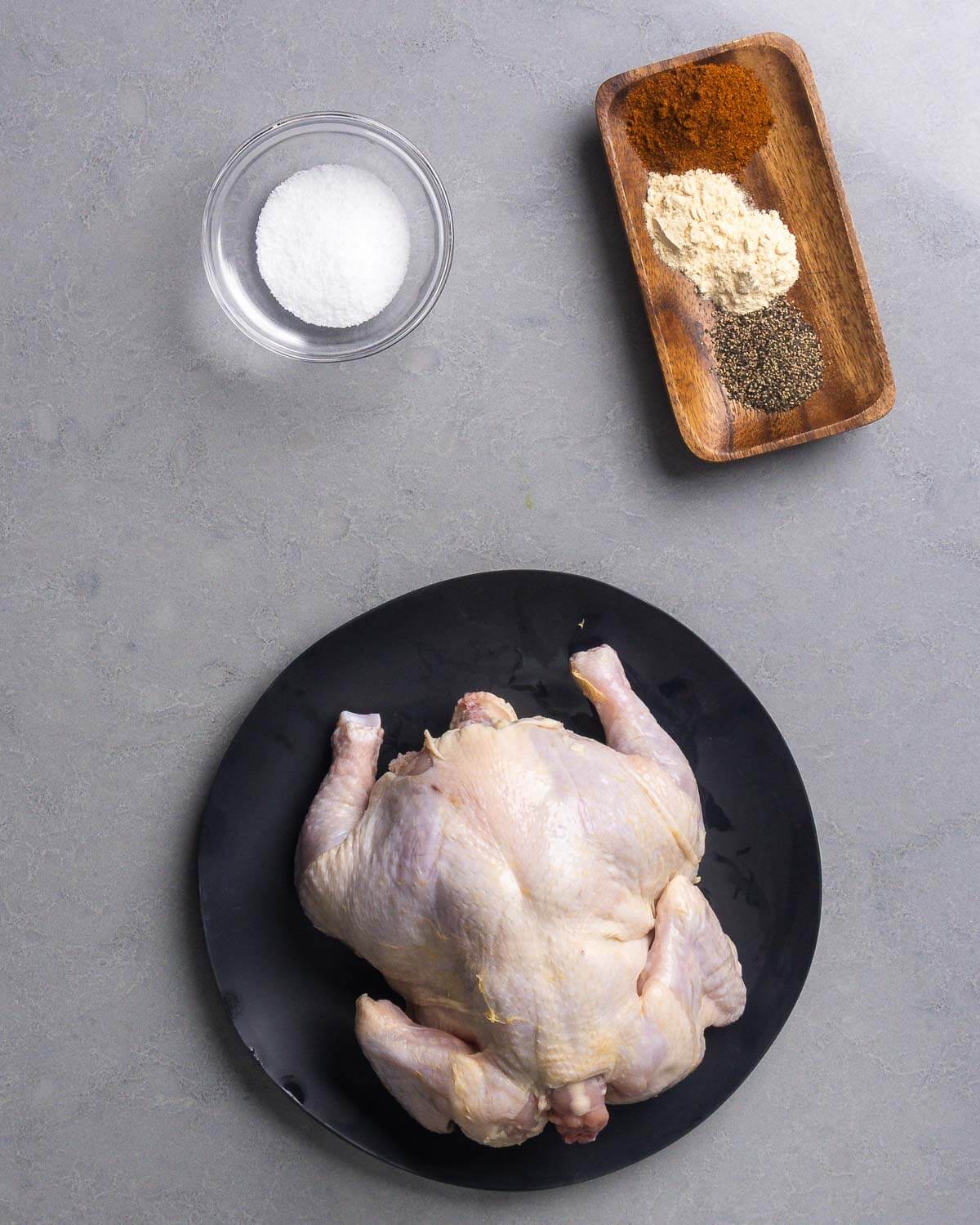 Ingredients shown: salt, paprika, garlic powder, onion powder, black pepper, and a whole chicken.