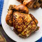 Two rotisserie chickens on white platter.