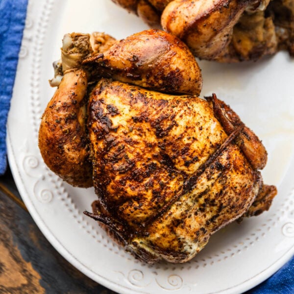 Two rotisserie chickens on white platter.