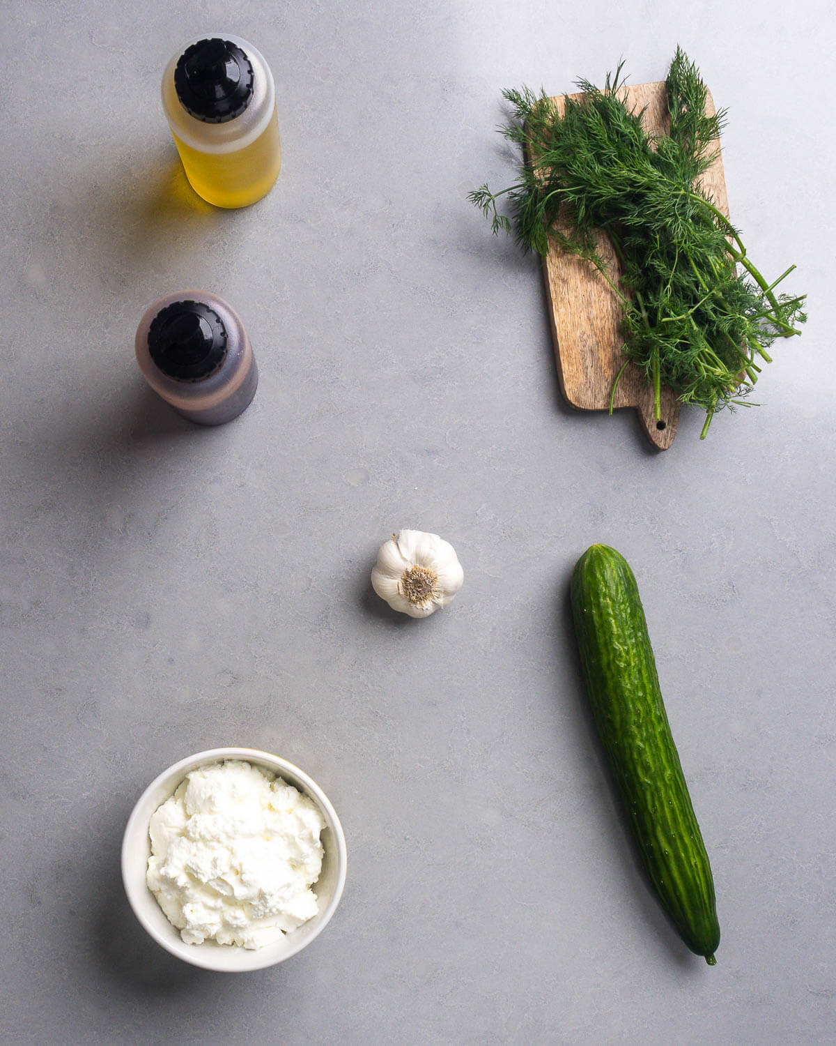 Ingredients shown: olive oil, red wine vinegar, dill, garlic, cucumber, and Greek yogurt.